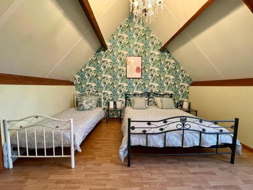 deux lits dans une chambre mansardée avec du papier peint vert dans l'établissement Gîte vue imprenable Vallée du Lot, piscine privée, à Calvignac
