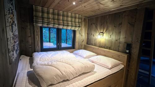 ein großes Bett in einem Zimmer mit Fenster in der Unterkunft Liaplassen Mountain Chalet - Beitostølen in Beitostøl