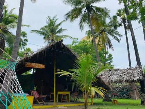 a black hut with palm trees in front of it at Delft Village Stay in Delft East