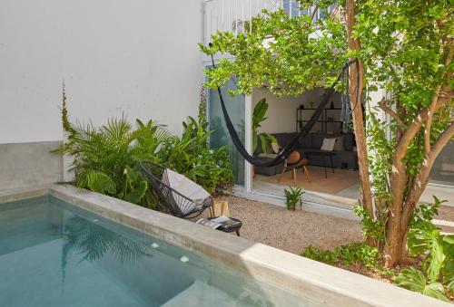 a swimming pool with a hammock in a garden at Casa Muliix in Mérida