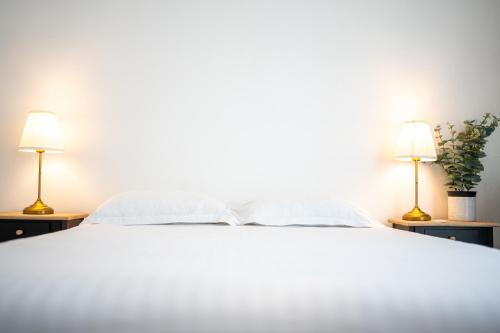 a bedroom with a white bed with two lamps at Villa Vichéia - Appartement 12 in Vichy