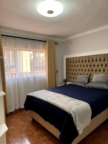 a bedroom with a large bed and a window at Nid De Chateau in Harare