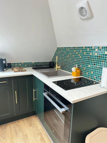 a kitchen with green cabinets and a sink at The Loft at Orchard House- Strictly No Parties in Barton in the Clay