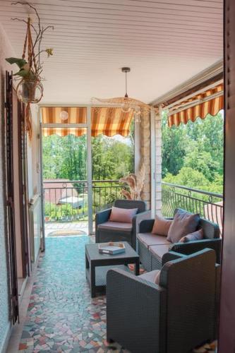 a living room with couches and a porch with a view at Le Ptit Abri in Les Avenières