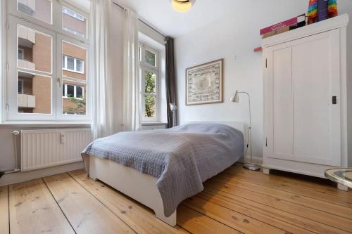 biała sypialnia z łóżkiem i 2 oknami w obiekcie Wunderschöne 3 Zimmer Wohnung! w mieście Hamburg