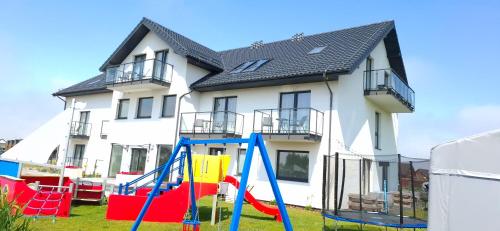 a house with a playground in front of it at Bursztynowa Rosa & Wypożyczalnia rowerów elektrycznych in Łeba