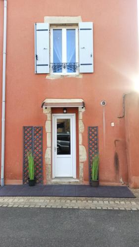 un bâtiment avec une porte blanche et deux plantes en pot dans l'établissement Charmante petite maison meublée, à Le Vernet