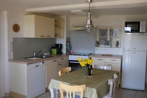 - une cuisine avec une table ornée de fleurs jaunes dans l'établissement Gite Fermette Francis à Lapoutroie, à Lapoutroie