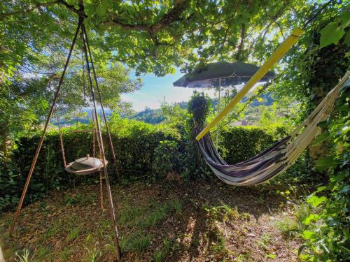 a hammock with an umbrella and a chair at O Cantinho de Coura - a cabana in Paredes de Coura