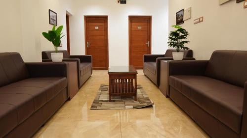 a waiting room with brown couches and a table at Neom's Golden Gate in Alwaye