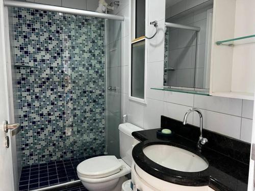 a bathroom with a toilet and a sink and a mirror at Apartamento aconchegante de frente para a praia in Fortaleza