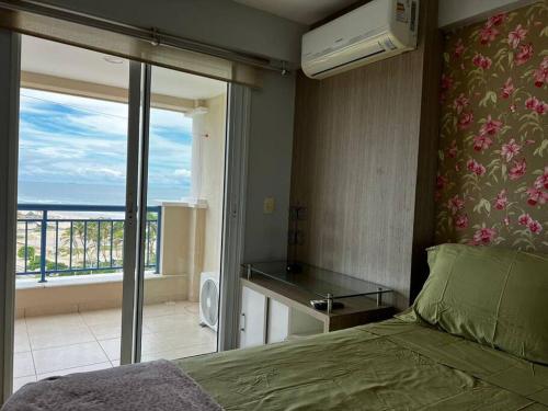 a bedroom with a bed and a view of the ocean at Apartamento aconchegante de frente para a praia in Fortaleza