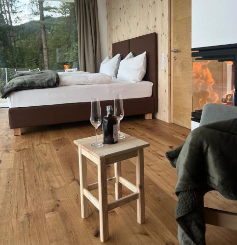 a bedroom with a bed and two wine glasses on a table at Chalet Tschattlhof Dolomites in Ponte Nova