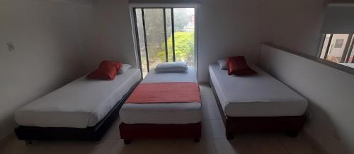 three beds in a room with a window at Hotel Laureles 70 Medellín in Medellín