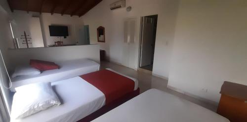 a hotel room with two beds and a television at Hotel Laureles 70 Medellín in Medellín