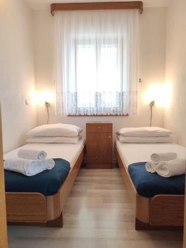 two beds in a room with a window at Apartments Glavinović - Near Beach and Center, Free Parking in Povlja