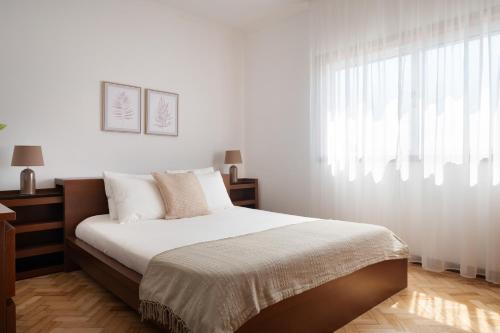 a white bedroom with a large bed with a window at KING SIZE Bed with Air Conditioning near the BEACH & FREE Street Parking in Canidelo