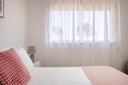 a white bedroom with a bed with a window at KING SIZE Bed with Air Conditioning near the BEACH & FREE Street Parking in Canidelo
