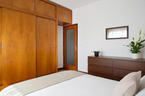 a bedroom with a bed and a wooden cabinet at KING SIZE Bed with Air Conditioning near the BEACH & FREE Street Parking in Canidelo