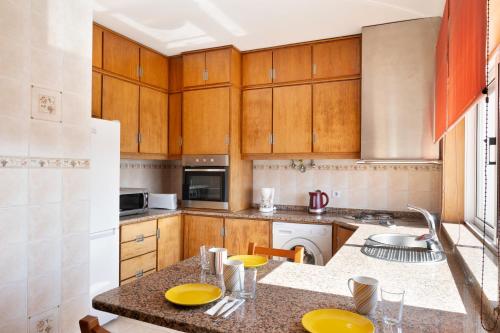 a kitchen with wooden cabinets and a counter top at KING SIZE Bed with Air Conditioning near the BEACH & FREE Street Parking in Canidelo