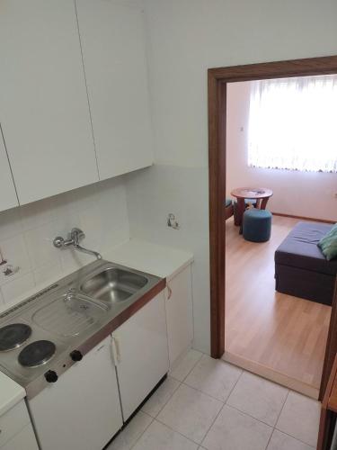 a kitchen with a sink and a living room at Apartments Glavinović - Near Beach and Center, Free Parking in Povlja