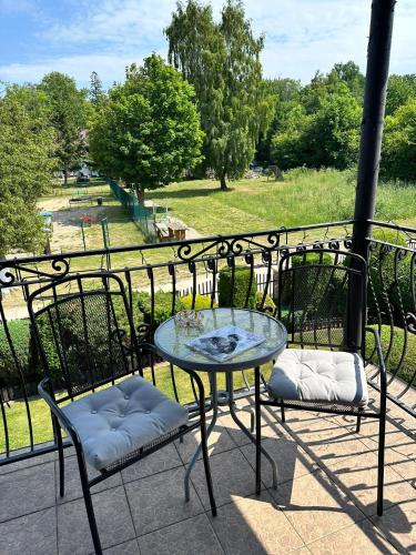 a glass table and two chairs on a balcony at Agrogajówka in Gniewino