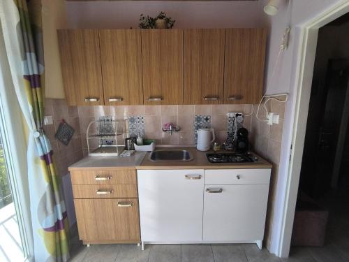 a small kitchen with wooden cabinets and a sink at Panoramic view studio in Rab