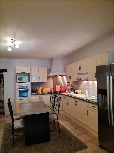 une cuisine avec des armoires blanches et une table avec des chaises dans l'établissement chez Maticouli, à Gaillac
