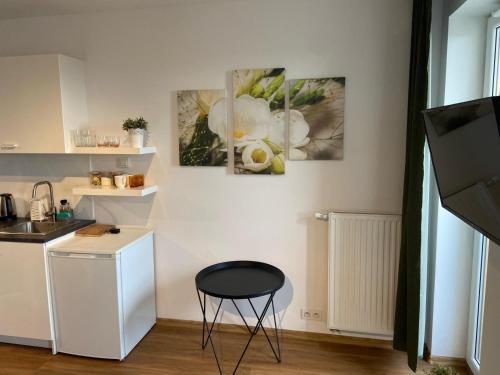 a kitchen with a stool and three paintings on the wall at Apartament Modlińska in Warsaw