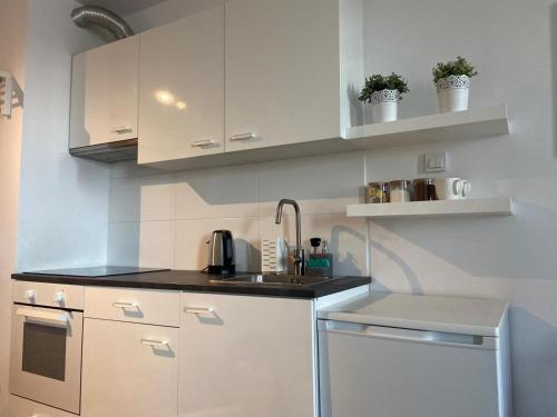 a kitchen with white cabinets and a sink at Apartament Modlińska in Warsaw