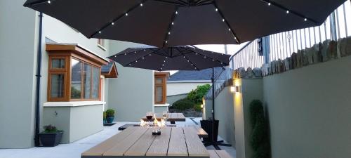 a patio with a wooden table and umbrellas at Harbour View Accommodation in Castletownbere