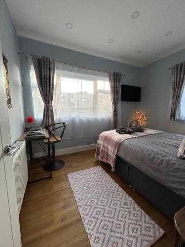 a bedroom with a bed and a desk and a window at Dana’s bungalow in Horley