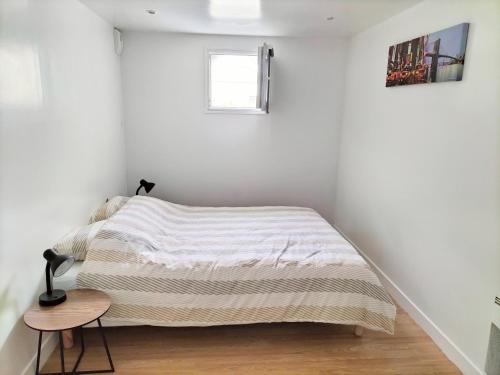 - une chambre blanche avec un lit et une petite table dans l'établissement Super appartement autonome a Villepinte proche de Paris, à Villepinte