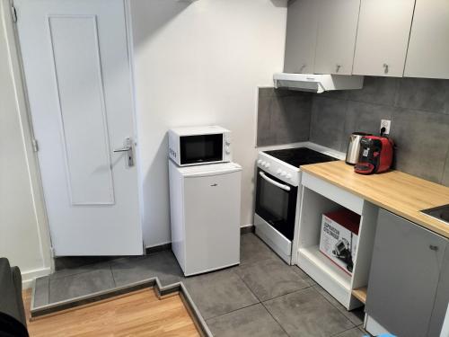 une petite cuisine avec des armoires blanches et un micro-ondes dans l'établissement Super appartement autonome a Villepinte proche de Paris, à Villepinte