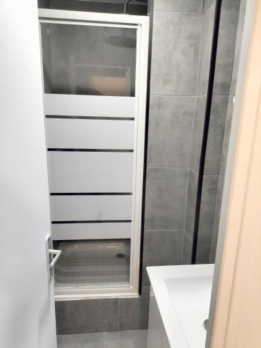 La salle de bains est pourvue d'une douche et d'un lavabo blanc. dans l'établissement Super appartement autonome a Villepinte proche de Paris, à Villepinte