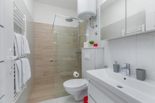 biała łazienka z toaletą i umywalką w obiekcie Apartments Ljiljana w Mimicach