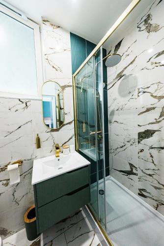 une salle de bain avec un lavabo et une douche en verre dans l'établissement L'Emeraude, à Saint-Brieuc