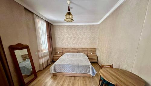 een slaapkamer met een bed, een spiegel en een tafel bij Racha guest house MERO in Ambrolauri