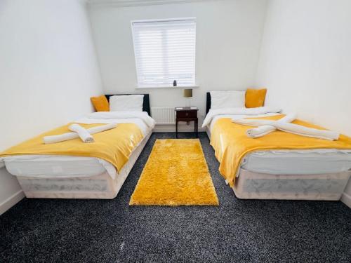 dwa łóżka w pokoju z żółtą pościelą w obiekcie Tranquil Haven: 3-BR House w mieście Great Burstead