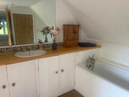 a bathroom with a sink and a mirror and a tub at 4 Lisle court cottages in Lymington