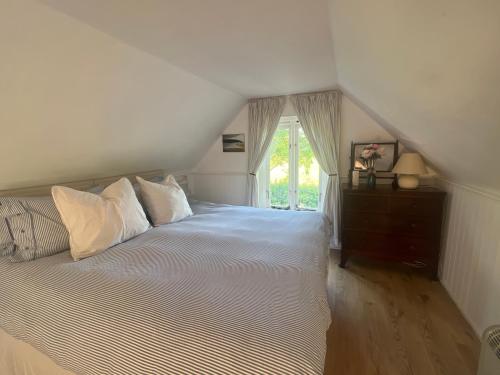 a bedroom with a bed with white sheets and a window at 4 Lisle court cottages in Lymington