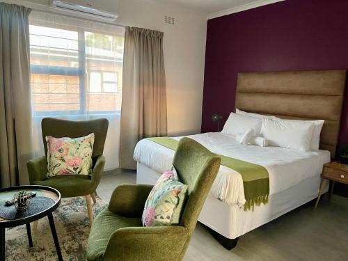ein Hotelzimmer mit einem Bett und zwei Stühlen in der Unterkunft Pristine Guest Apartments in Mthatha