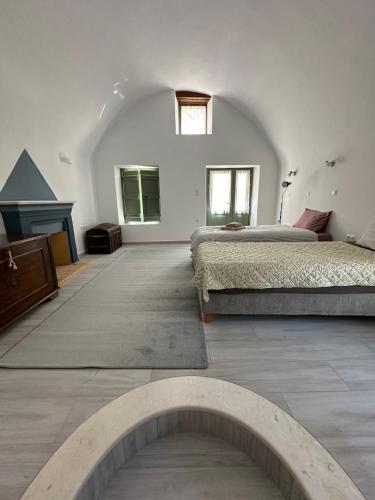 a white bedroom with two beds and a fireplace at Alexander House 1 in Leonidion