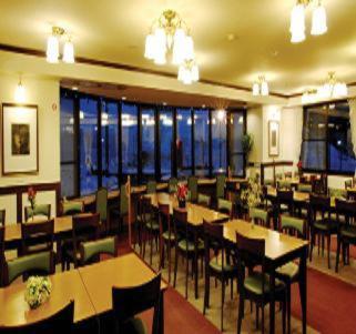 a restaurant with tables and chairs and windows at Hakuba Yamano Hotel in Hakuba