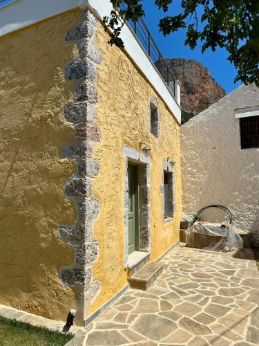 a yellow building with a stone wall and a door at Alexander House 1 in Leonidion