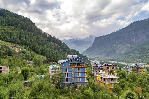 a group of buildings on a hill with mountains at Zostel Old Manali, Goshal Road in Manāli