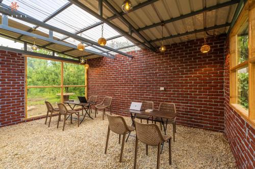 a room with tables and chairs and a brick wall at Zostel Old Manali, Goshal Road in Manāli