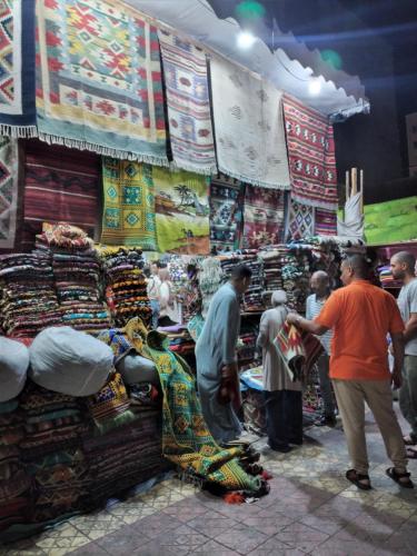 um grupo de pessoas em pé em um mercado com tapetes em شقة 2 غرفة بتكييف em Marsa Matruh