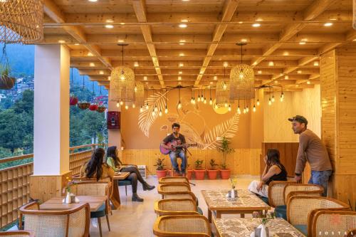 a group of people sitting in a restaurant with a guitarist at Zostel Old Manali, Goshal Road in Manāli