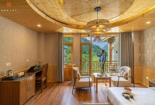 a hotel room with a bed and a desk and a large window at Zostel Old Manali, Goshal Road in Manāli